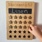 Kind setzt einen Stern auf eine Belohnungstafel aus Holz und sammelt Punkte für erledigte Aufgaben